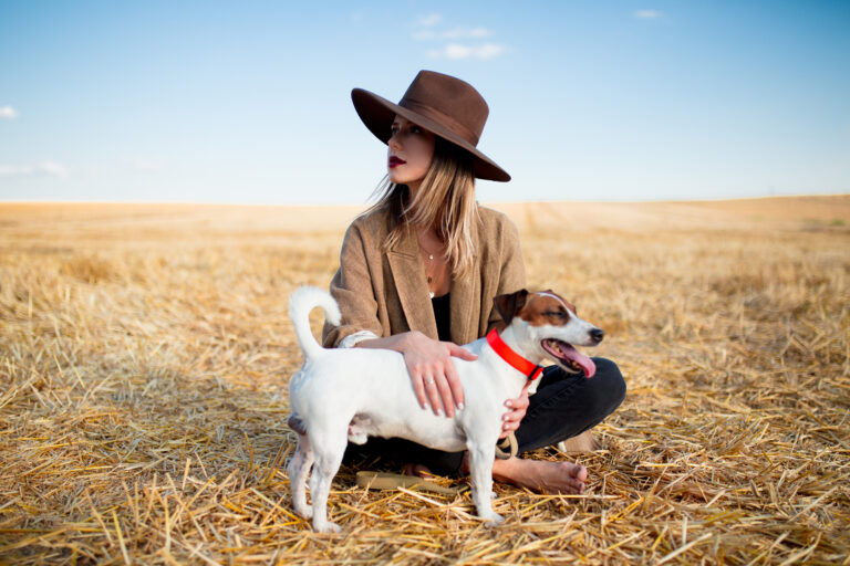 Woman in hat with dog on field